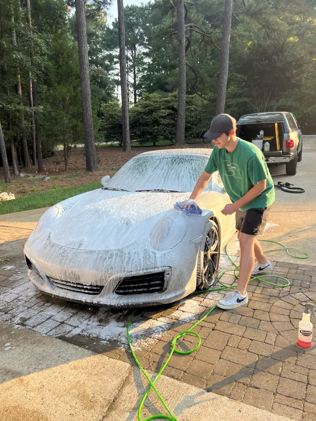 Washing a white sports car with a sponge